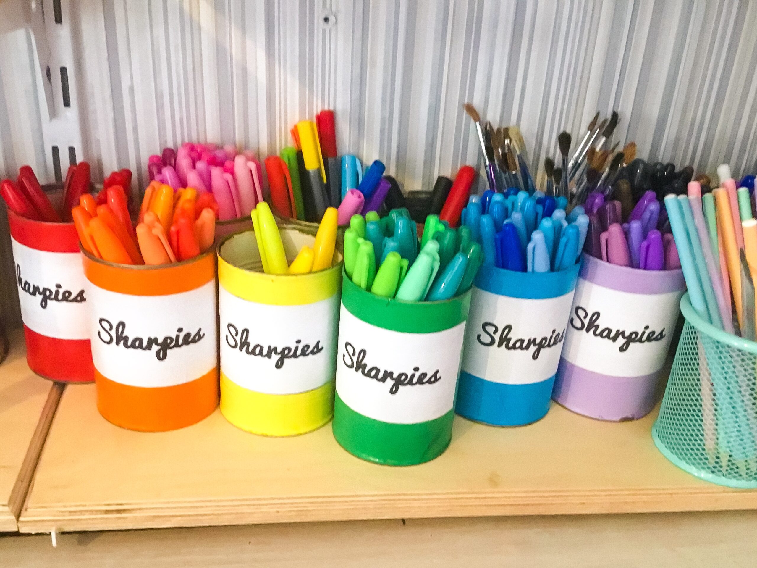 Multi coloured sharpies in handmade colour coordinated pen pots.